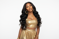 light skin african american woman wearing glmaour gold 2 piece attire, modeling long black body wave hair, looking in the direcrion of the camera, head tilted to the side, natural glam makeup, white studio bakcground, gold accessories, simple pose, focusing on the hair