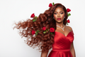 ultra realistic hair model with soft glam making with hints of red, red lipstick, valentines day photoshoot, long thick body wave hair, with roses throughout the hair, highlight the hair, white studio background, model is wearing luxurious chic red dress, african american model, subtle diamond jewelry